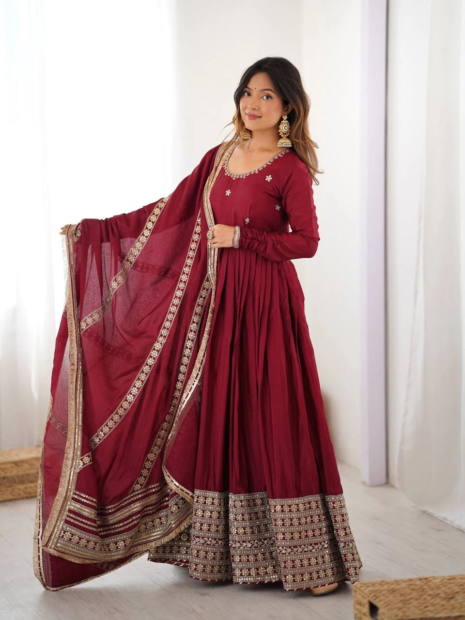 Woman wearing a maroon traditional outfit with gold details indoors.