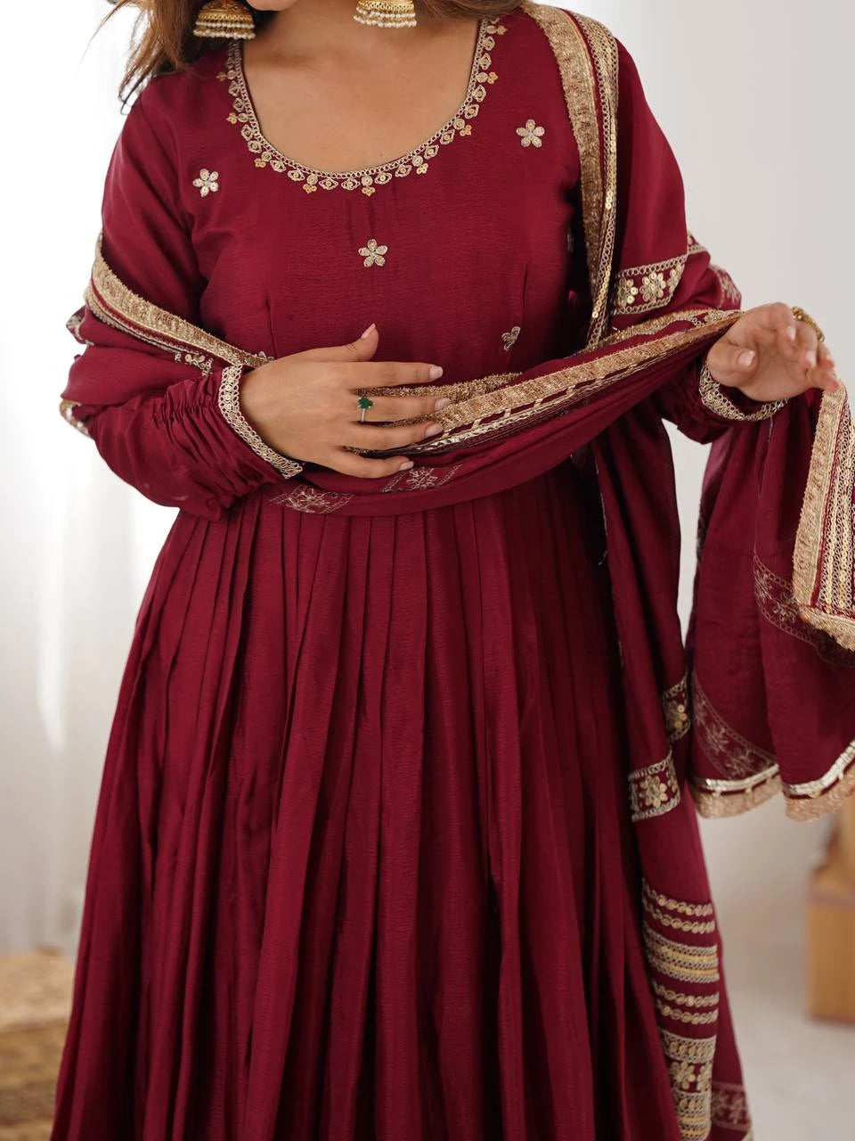 Maroon traditional outfit with gold embroidery on a plain background