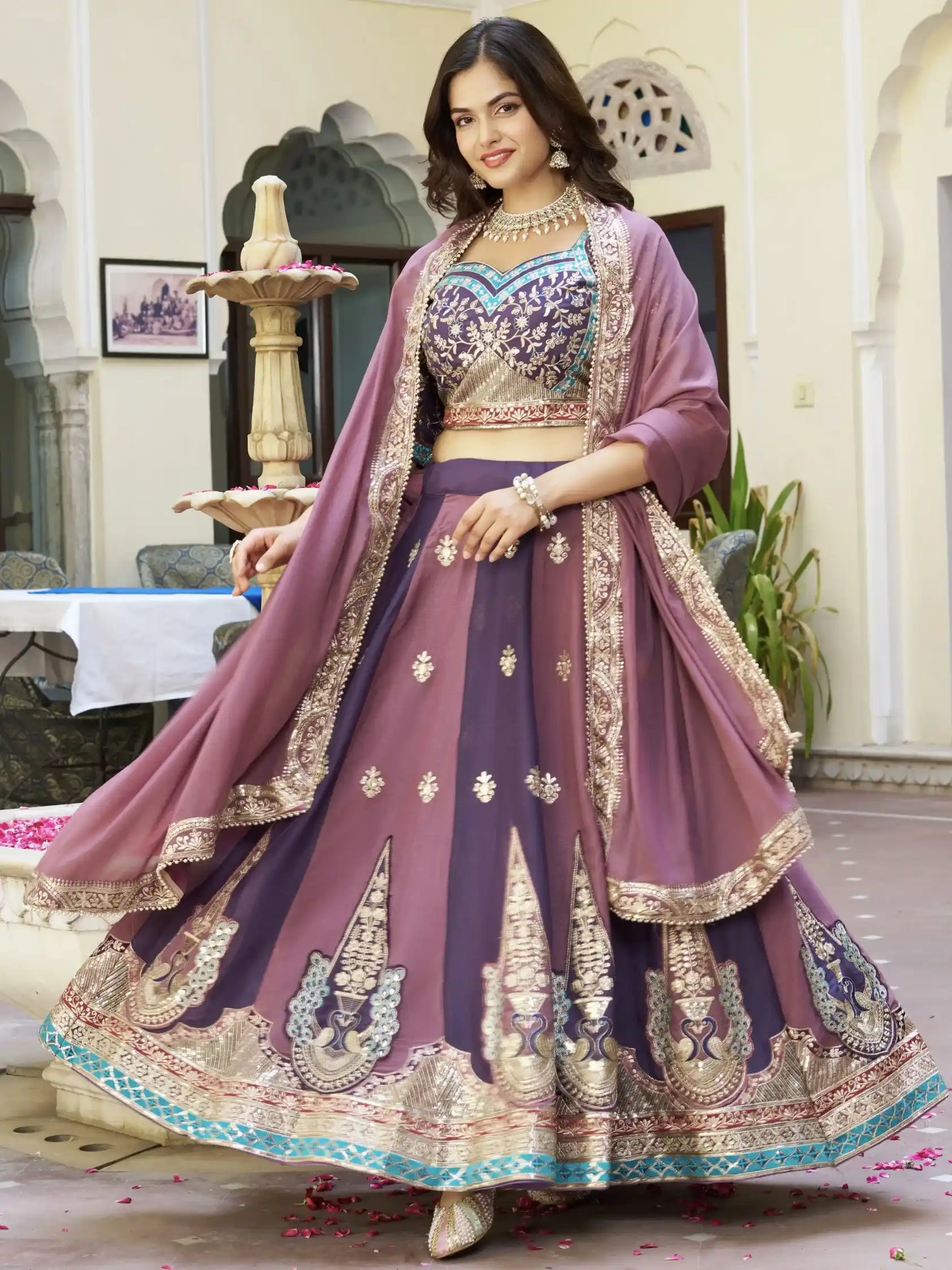 Woman in a traditional outfit with intricate designs in a decorated indoor setting