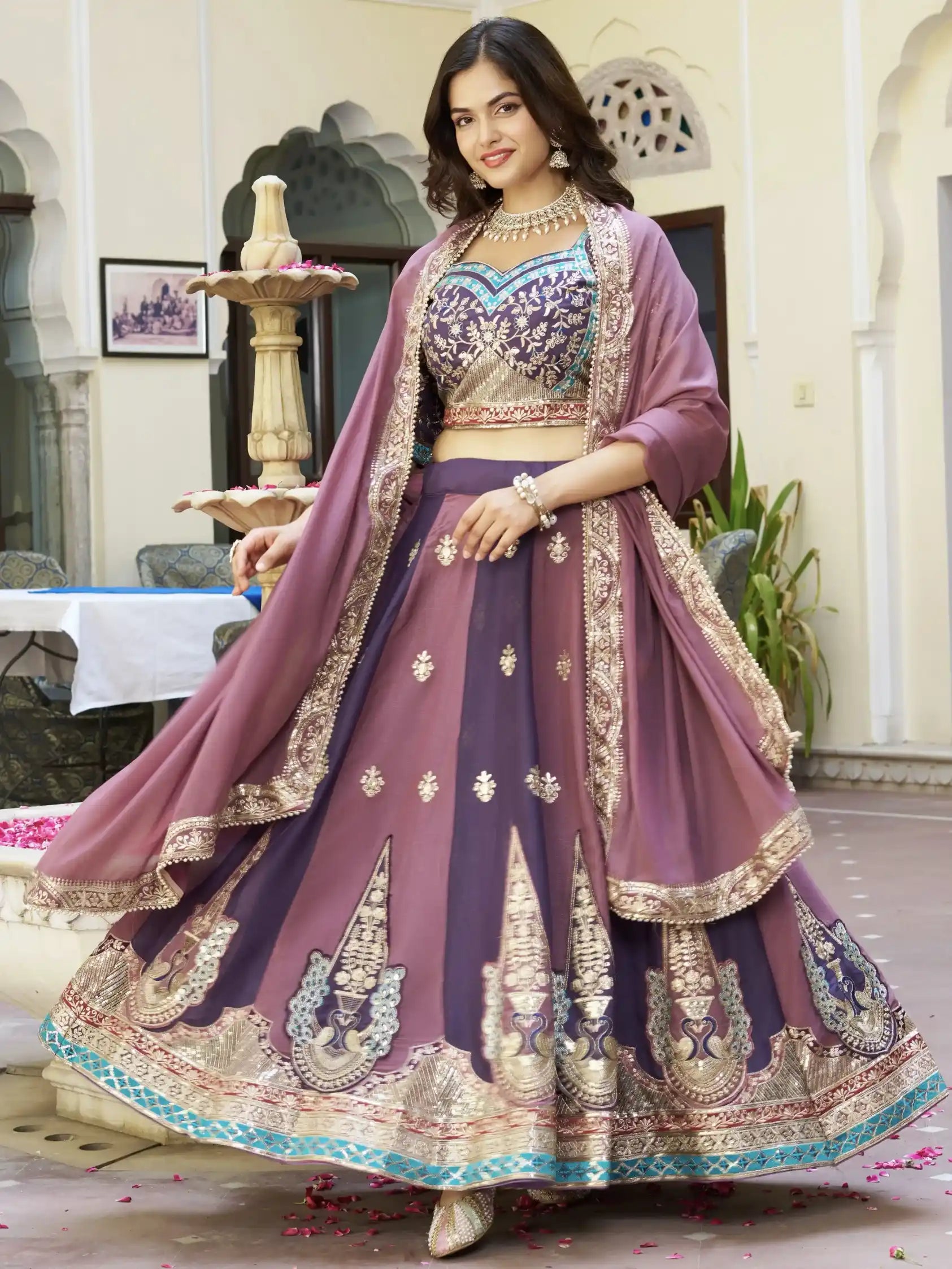 Woman in a traditional outfit with intricate designs in a decorated indoor setting