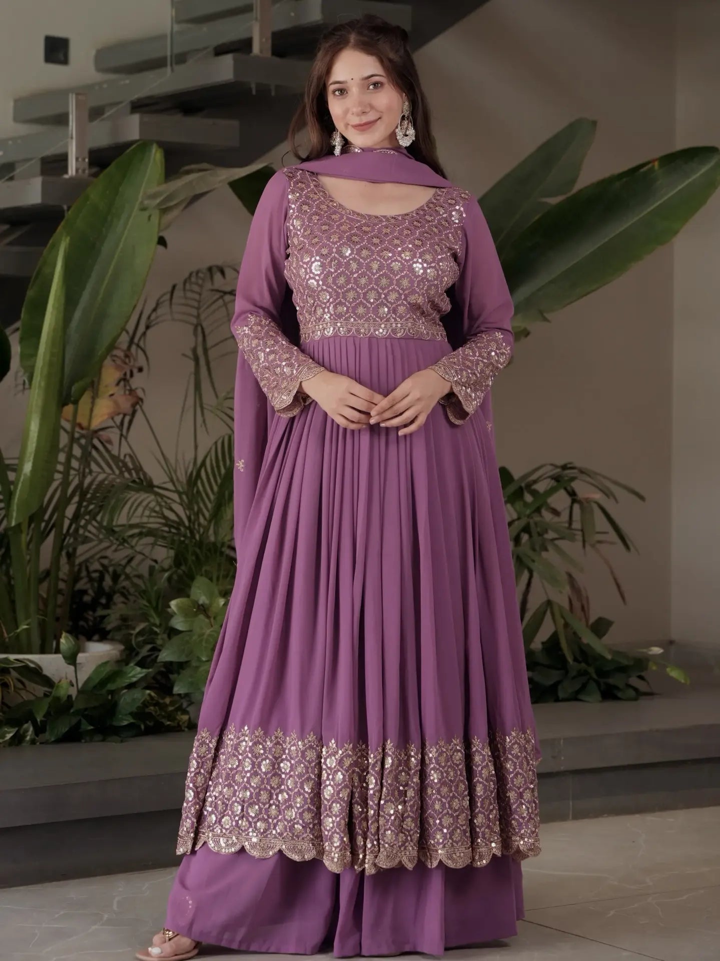Woman wearing a purple traditional outfit with floral patterns indoors.