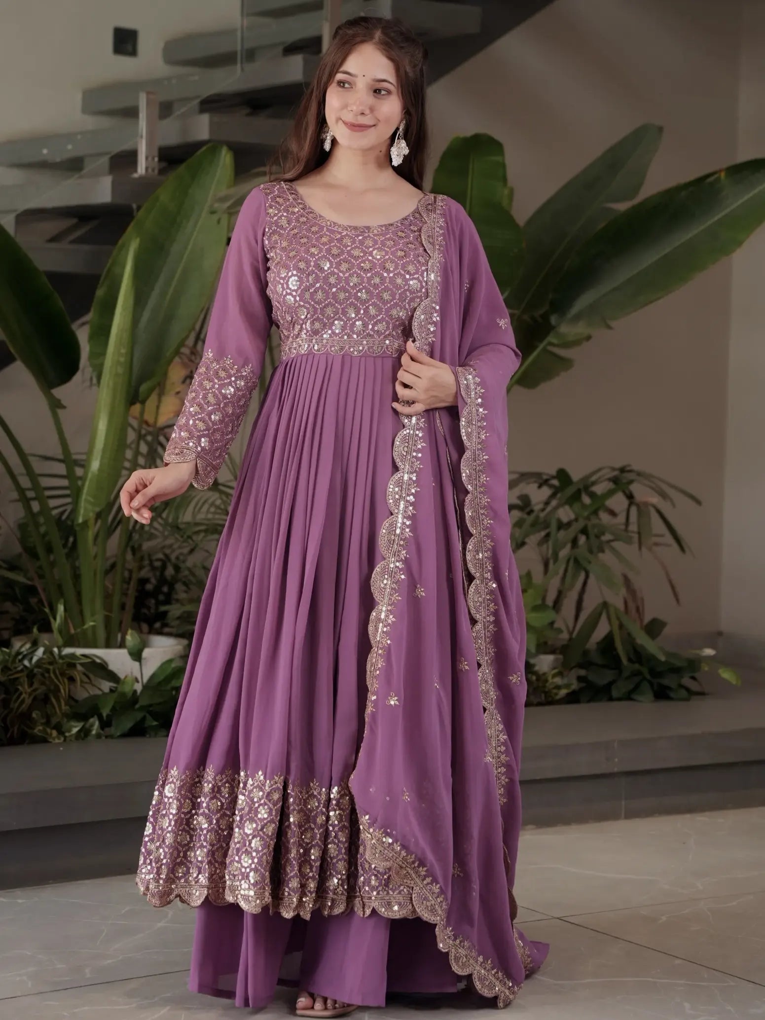 Woman wearing a purple embroidered dress in an indoor setting with plants.