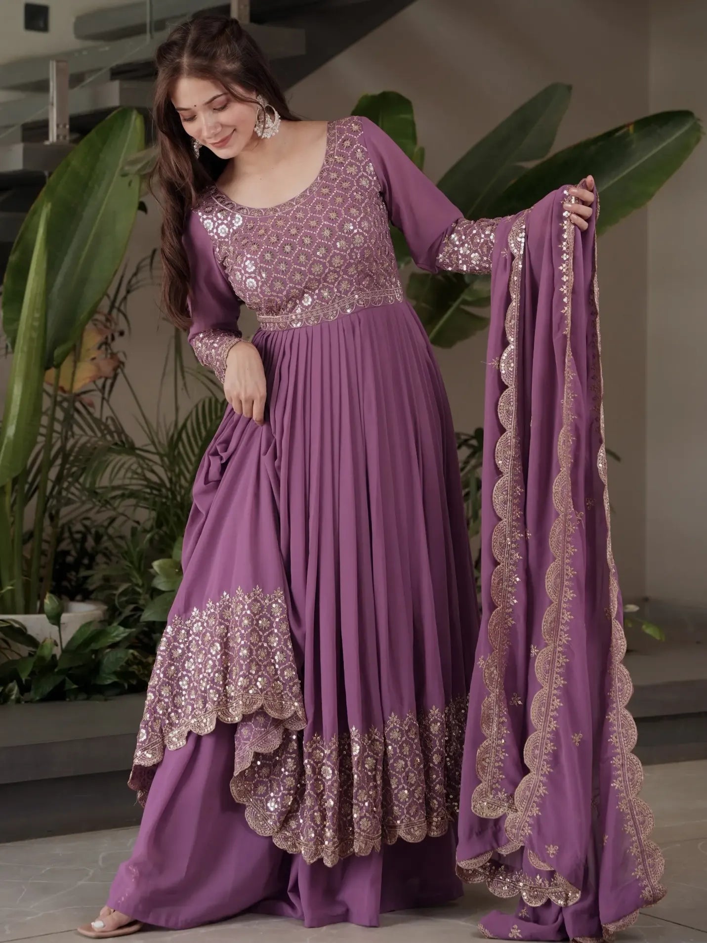 Woman wearing a purple traditional outfit with gold embroidery, holding a matching dupatta.