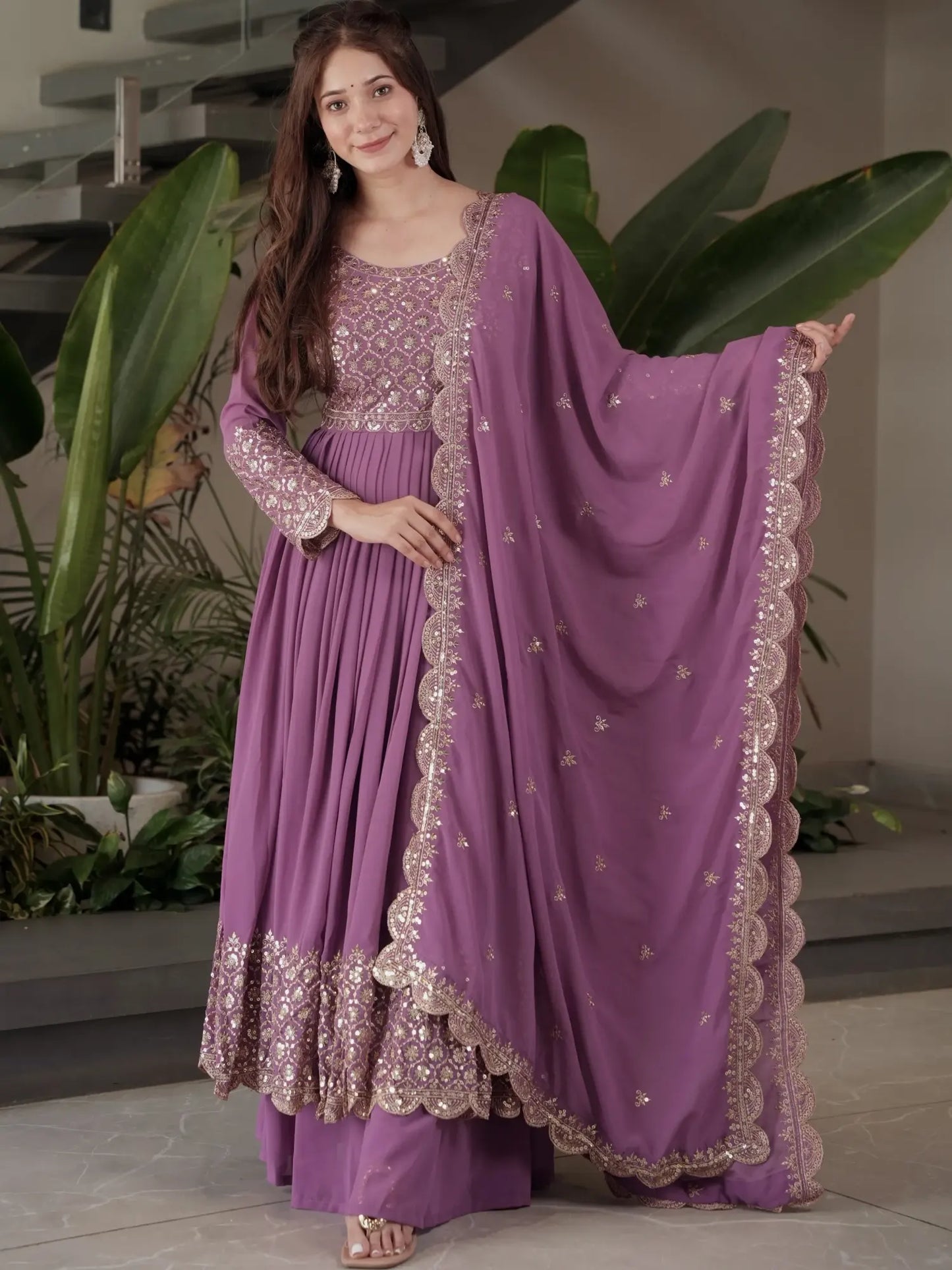 Woman wearing a purple traditional outfit with a matching dupatta in an indoor setting.
