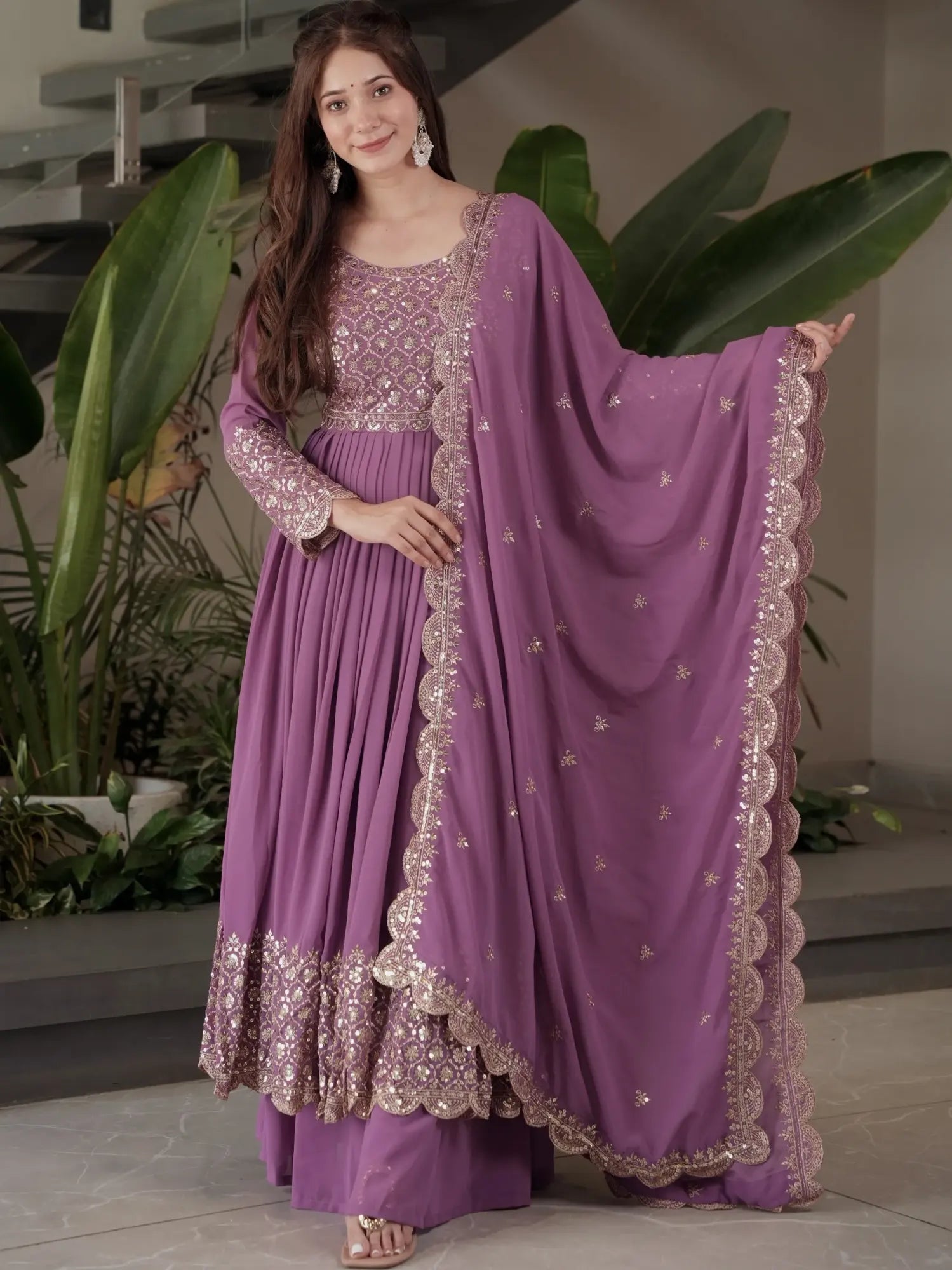 Woman wearing a purple traditional outfit with a matching dupatta in an indoor setting.