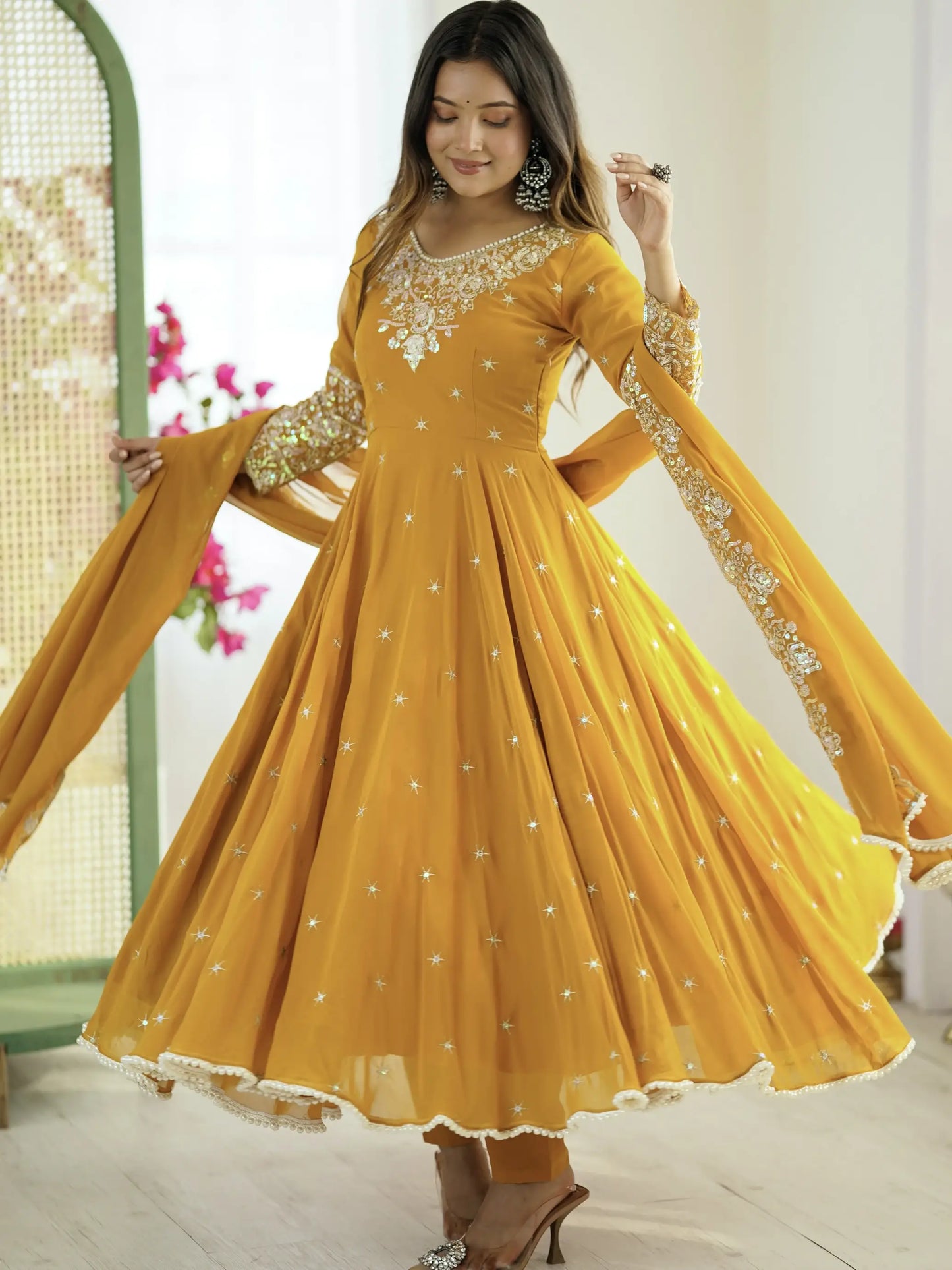 Woman wearing a yellow embroidered anarkali suit with a white background