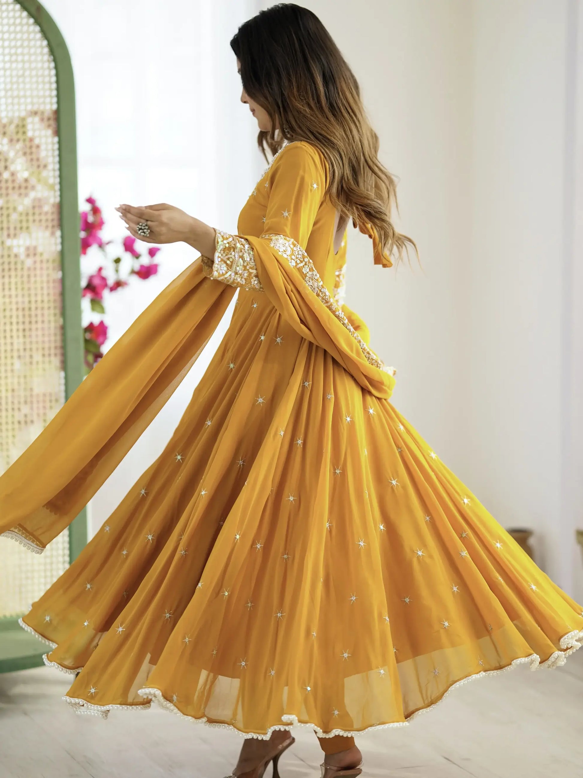 Woman wearing a yellow dress with floral patterns in a bright setting