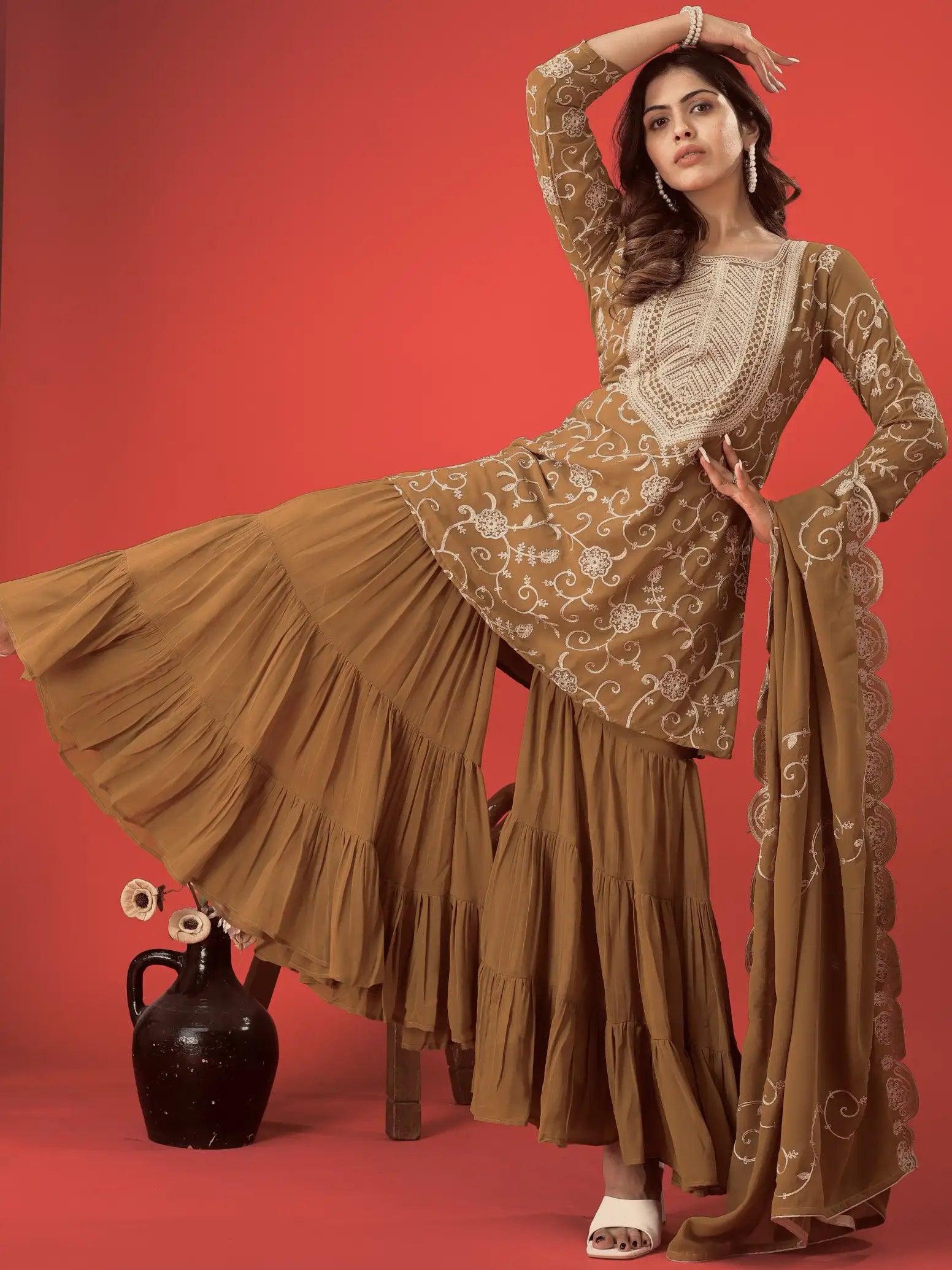 Woman in a traditional outfit with intricate patterns on a red background
