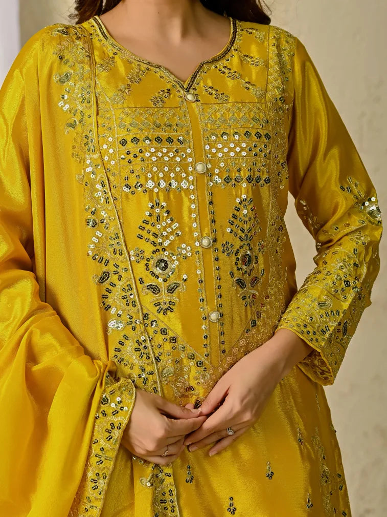 Yellow embroidered traditional outfit with intricate patterns on a neutral background