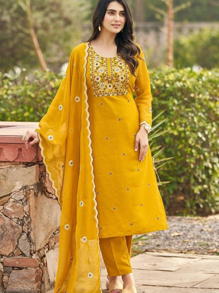 Woman wearing a yellow traditional outfit with floral patterns outdoors.