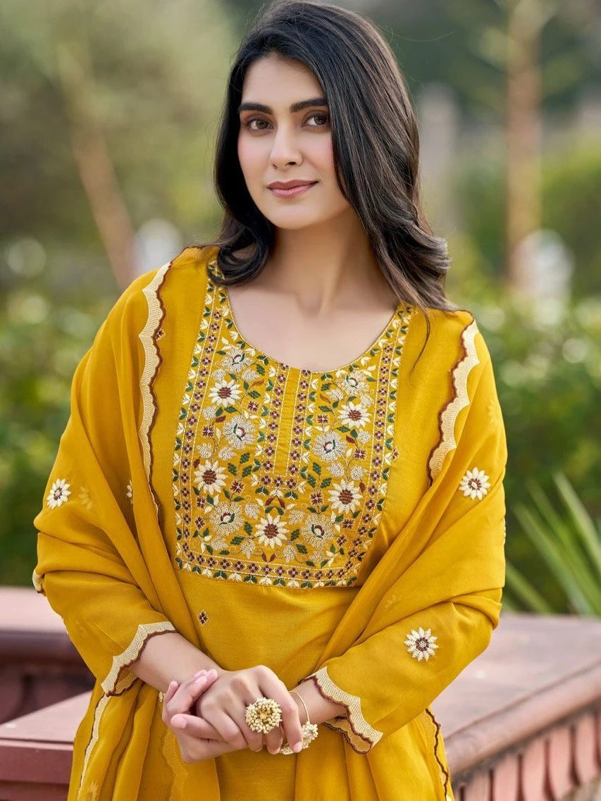 Woman wearing a yellow traditional outfit with floral patterns outdoors.