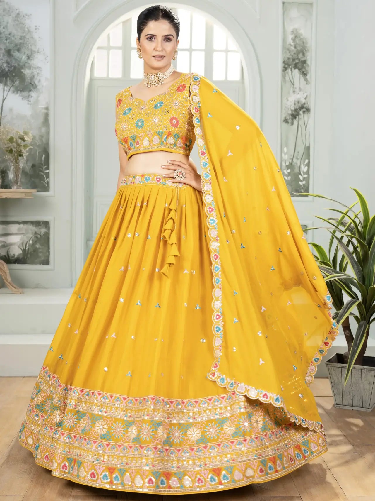 Woman wearing a yellow traditional outfit with floral patterns indoors.