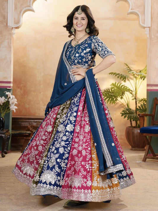 Woman wearing a colorful traditional outfit with a blue and pink design in an indoor setting.