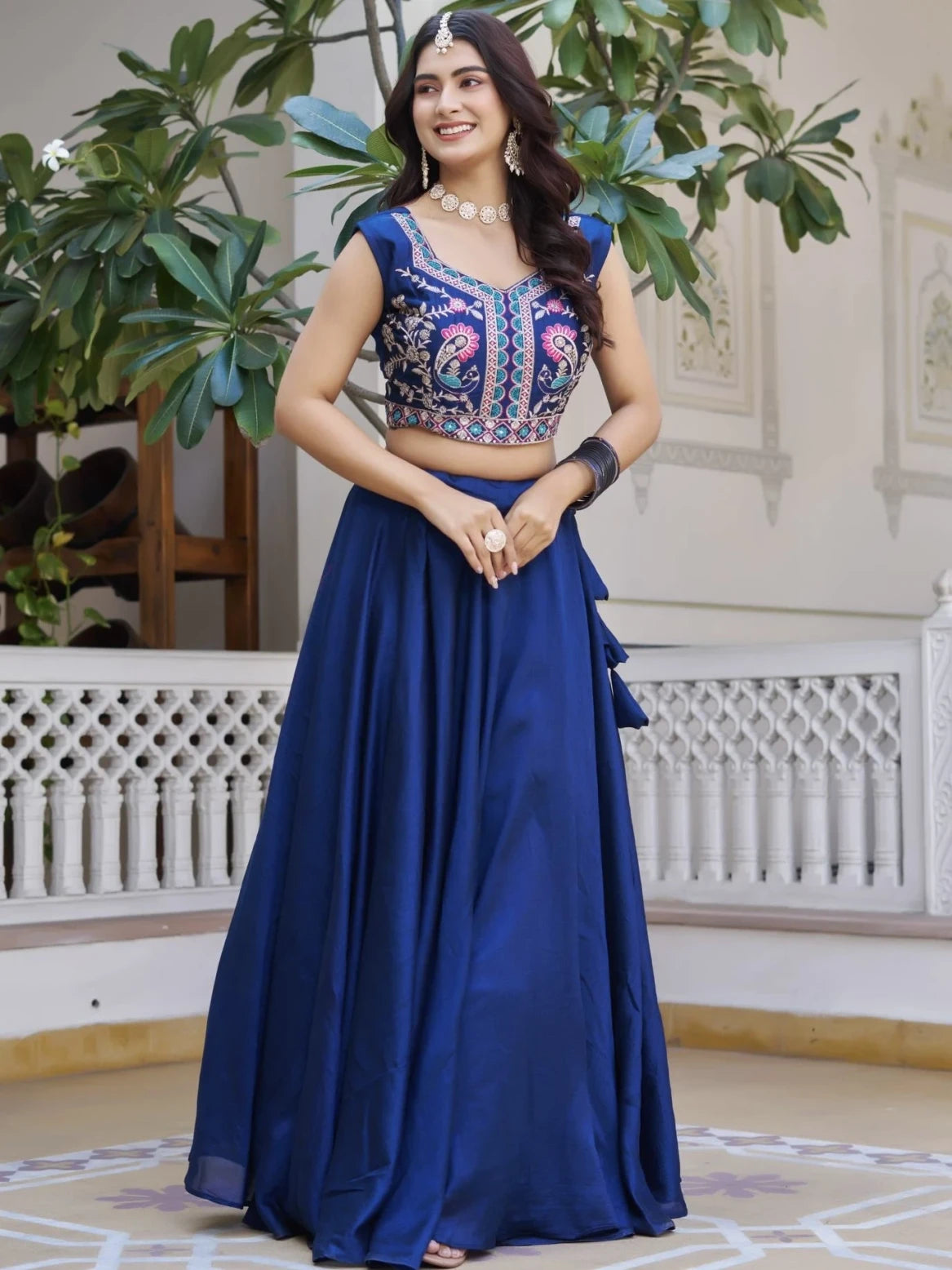 Woman wearing a blue traditional outfit with a floral blouse in an indoor setting.
