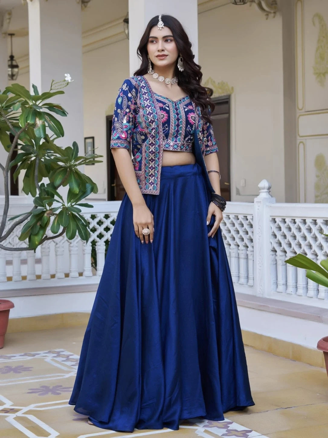 Woman wearing a blue traditional outfit with a floral top in an indoor setting.