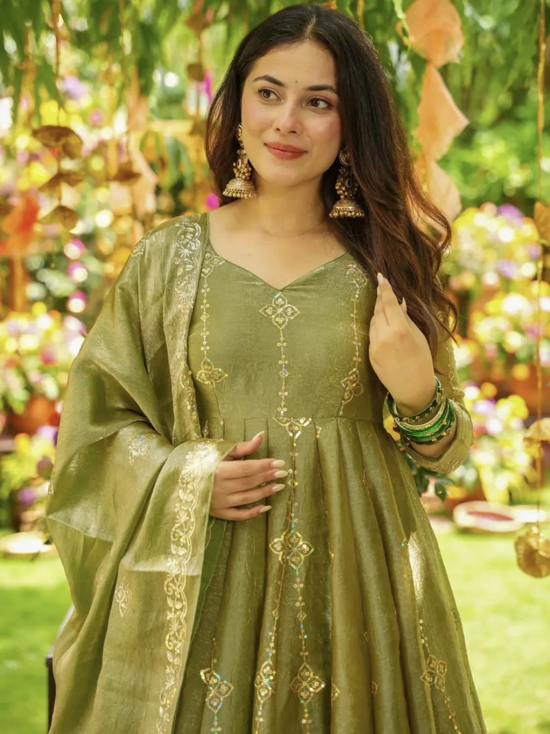 Woman in a green traditional outfit with floral decorations in the background