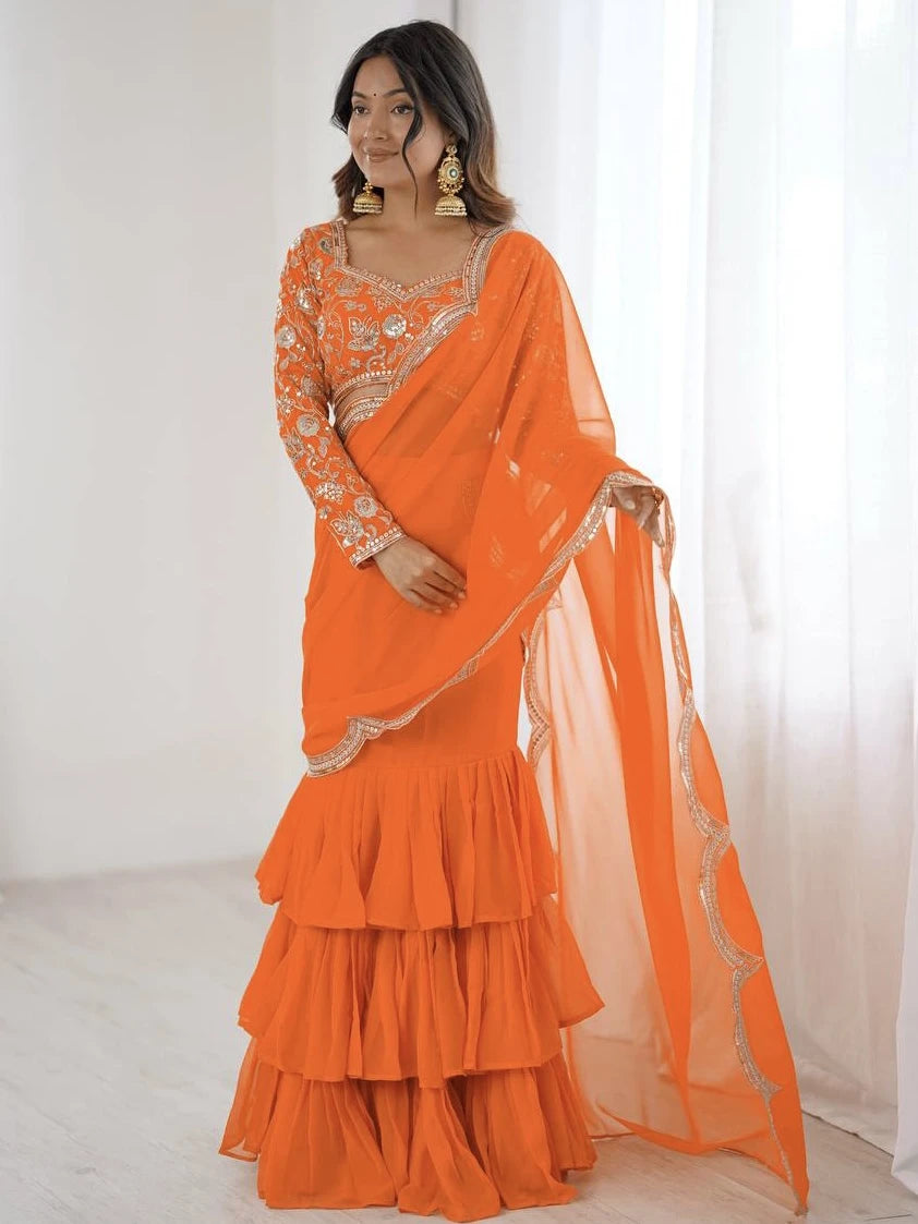 Woman wearing an orange traditional outfit with a sheer dupatta against a white background