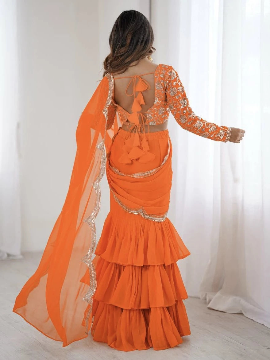 Orange evening gown with sheer overlay and ruffled layers on a white background