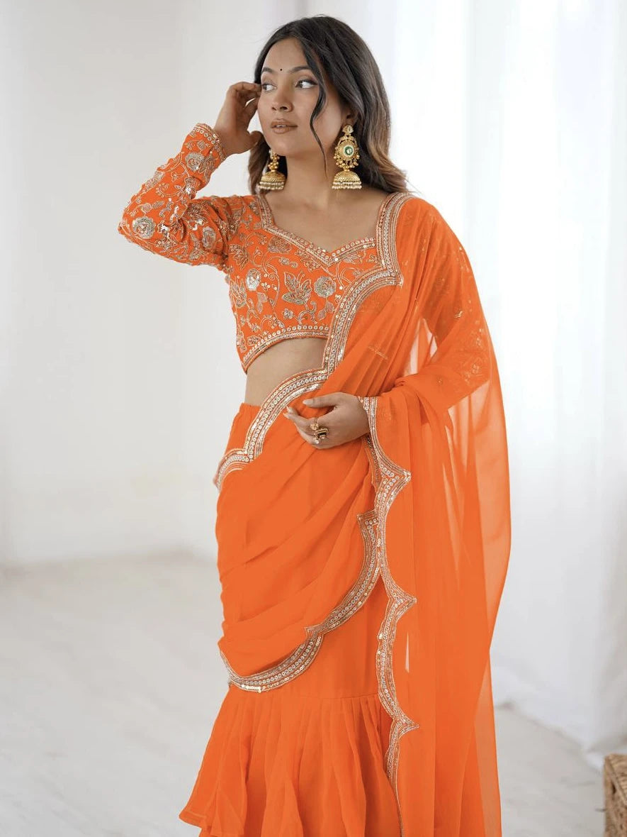 Woman wearing an orange saree with gold embroidery against a white background