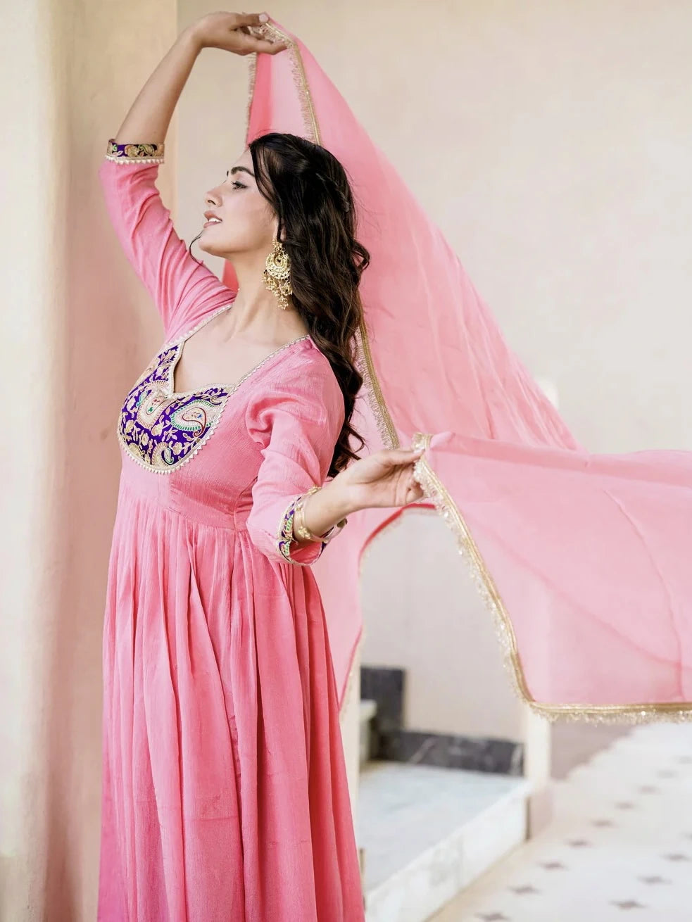 Woman in a pink traditional outfit with a long scarf, indoors.
