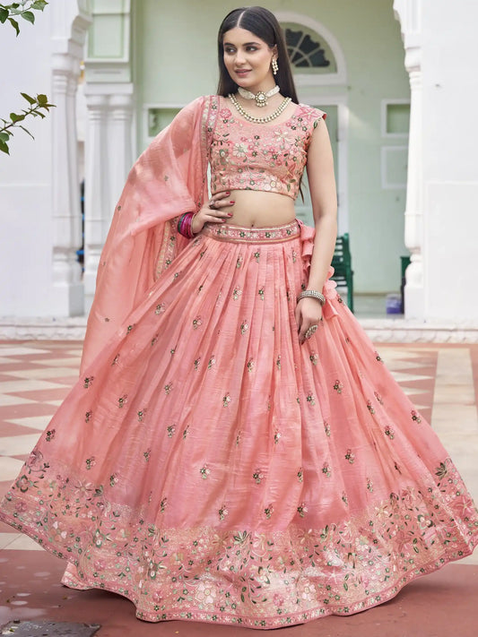 Woman wearing a pink embroidered traditional outfit in front of a white building.