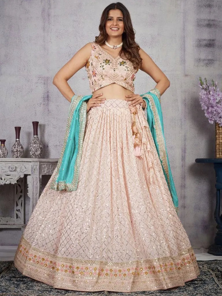 Woman wearing a traditional outfit with a pink lehenga and blue dupatta against a neutral background.