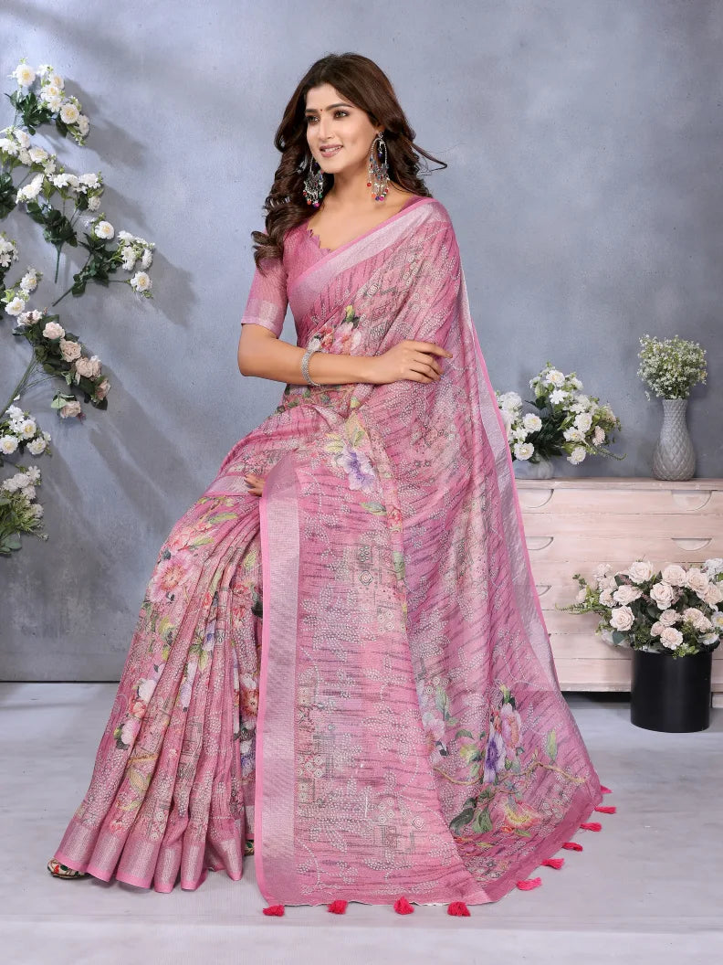 Woman wearing a pink saree with floral patterns in a decorated indoor setting.