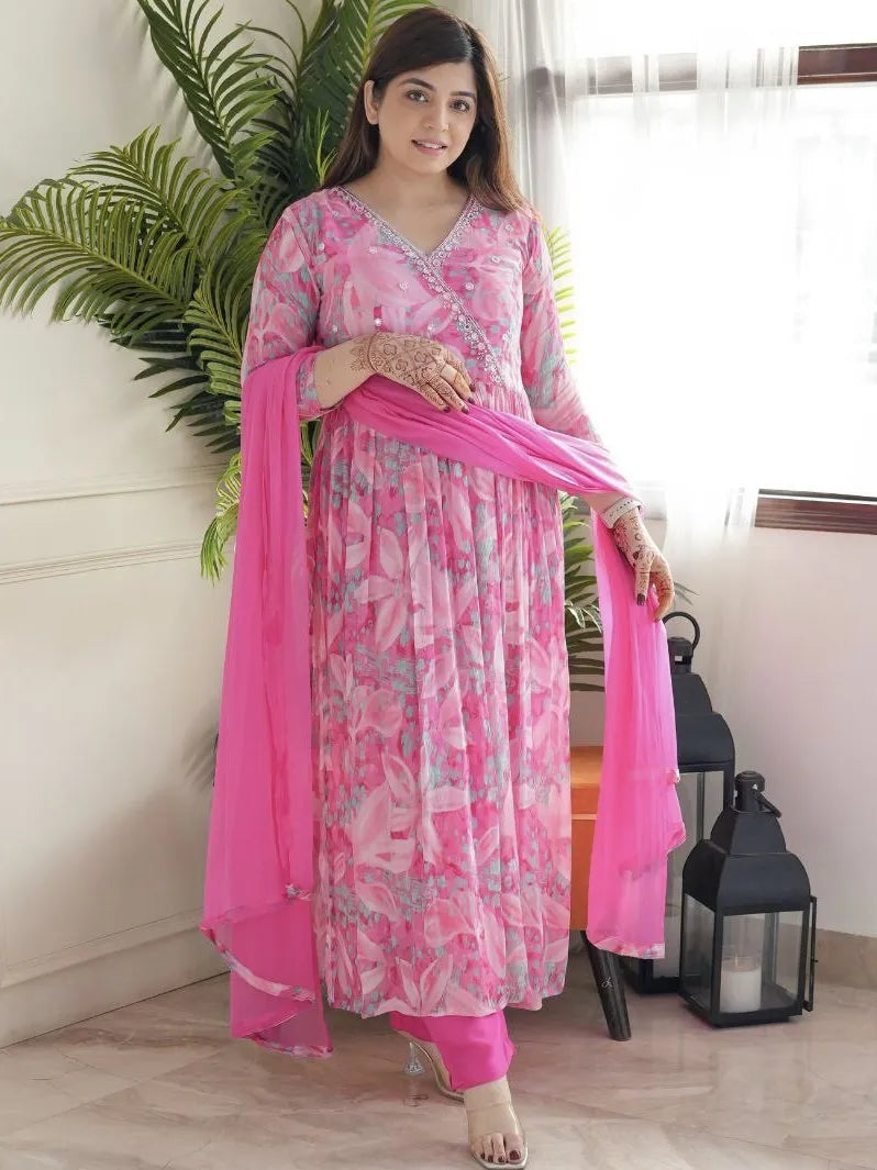 Woman wearing a pink floral dress with a matching dupatta indoors.