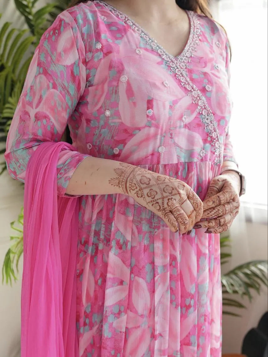 Person wearing a pink floral dress with intricate henna designs on hands