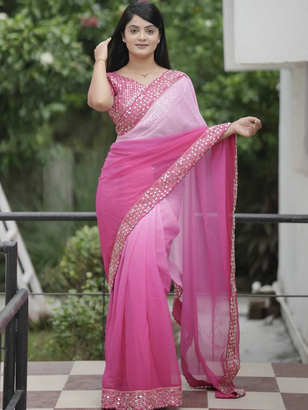 Woman wearing a pink saree with a white blouse outdoors.