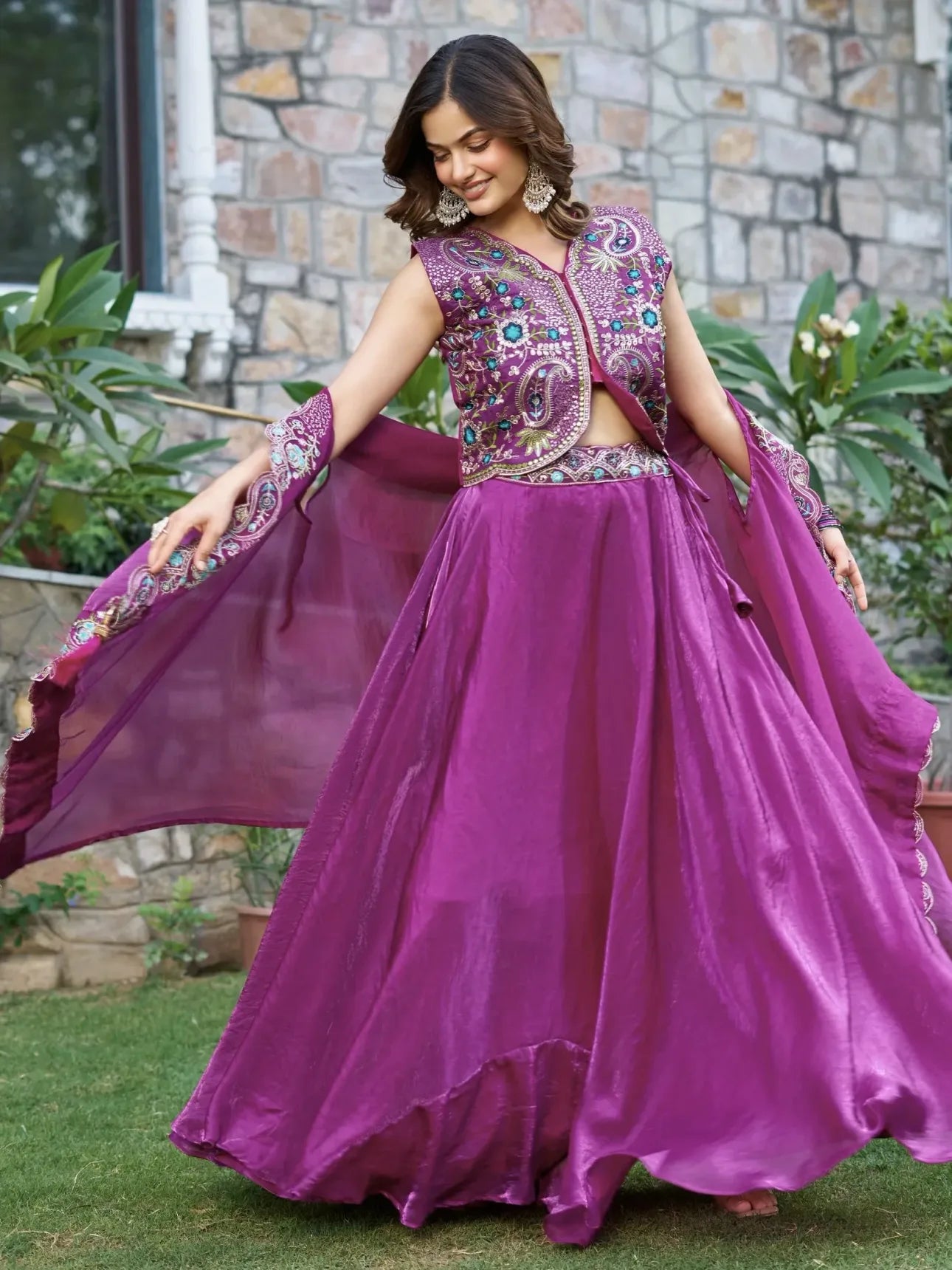 Woman in a vibrant purple traditional outfit with floral patterns outdoors.