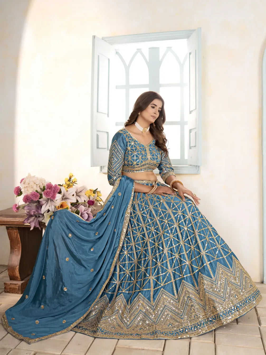 Woman in a blue and gold traditional outfit with a flowing skirt in a bright room.