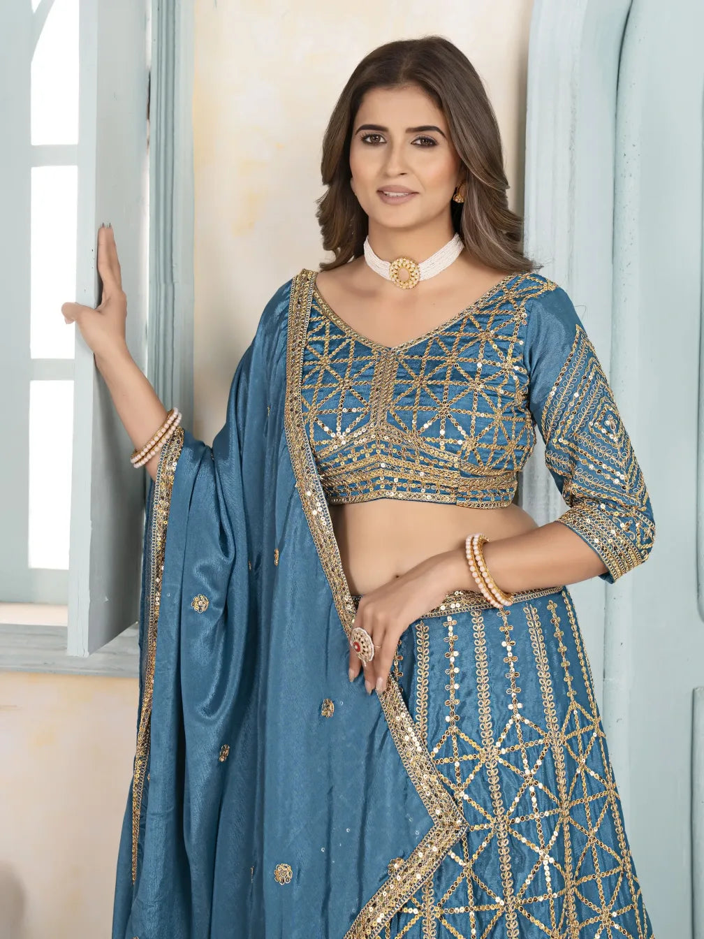 Woman wearing a blue embroidered traditional outfit with gold details.