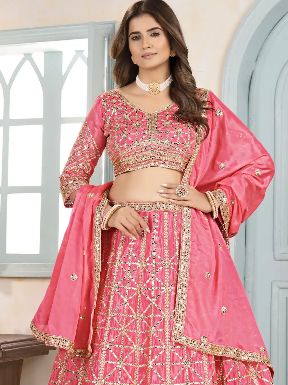 Woman wearing a pink embroidered traditional outfit indoors.