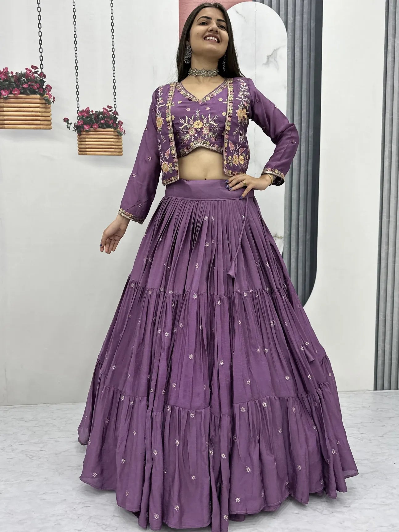 Woman wearing a purple traditional outfit with floral patterns indoors.