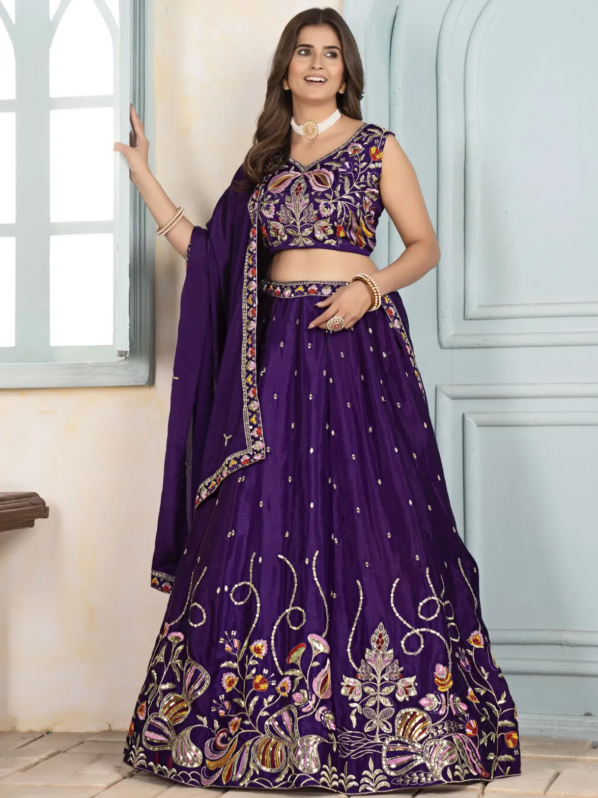 Woman wearing a purple embroidered traditional outfit with a matching dupatta.