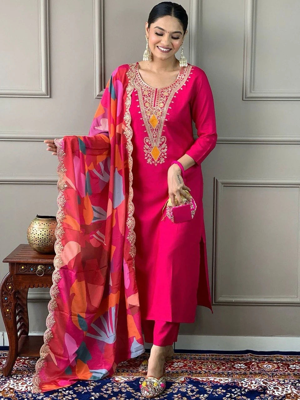 Woman in a bright pink traditional outfit with colorful dupatta indoors.