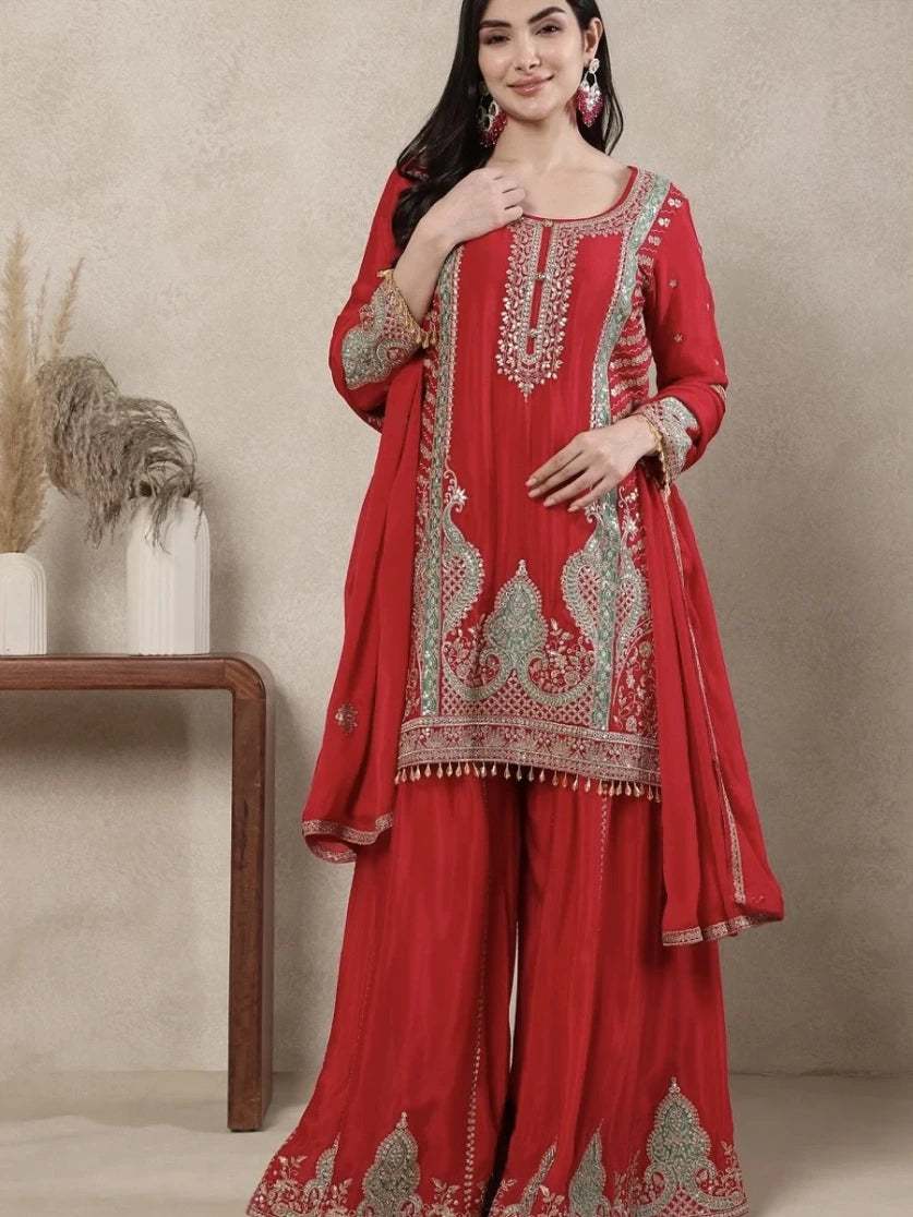 Woman wearing a red embroidered traditional outfit against a neutral background