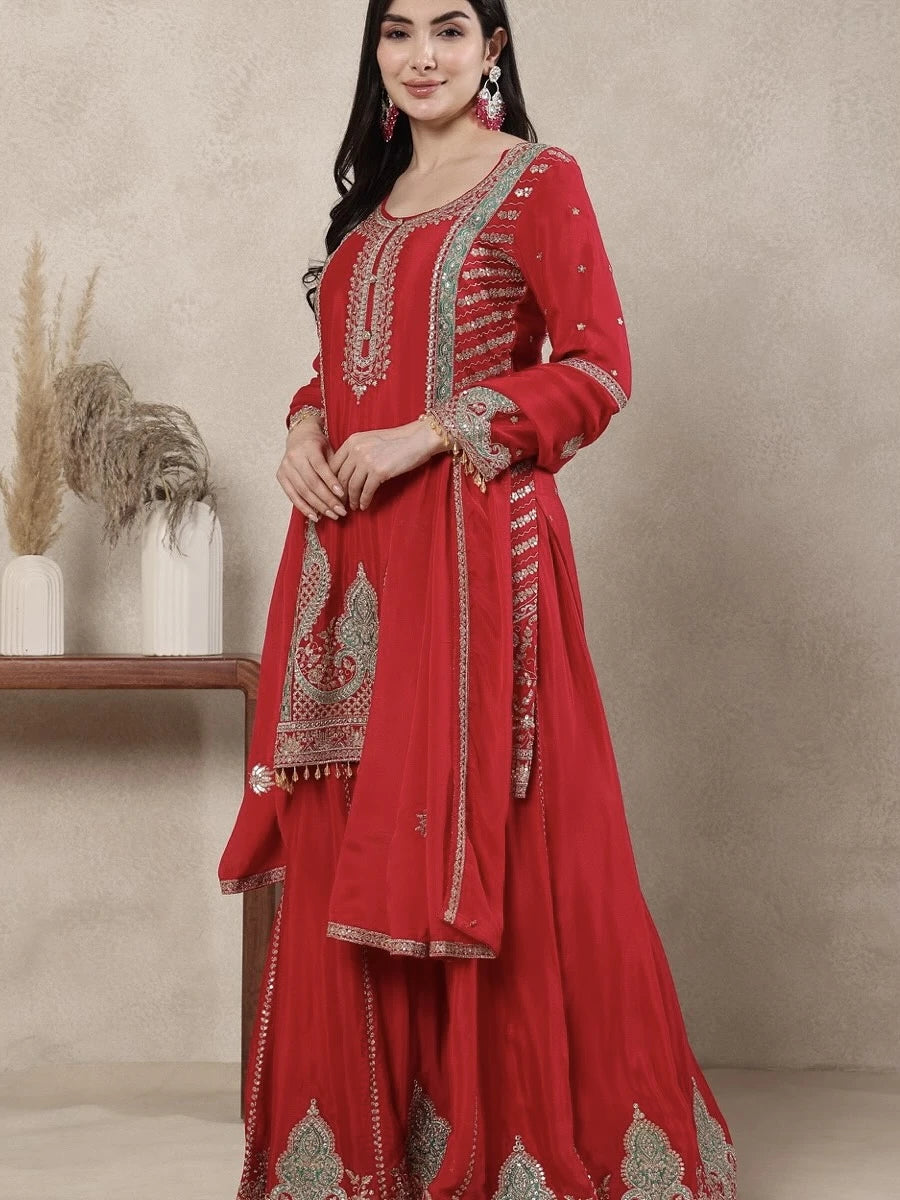 Woman wearing a red embroidered traditional outfit against a neutral background