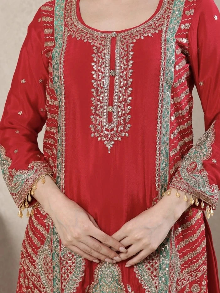 Red embroidered traditional outfit with intricate patterns on a neutral background