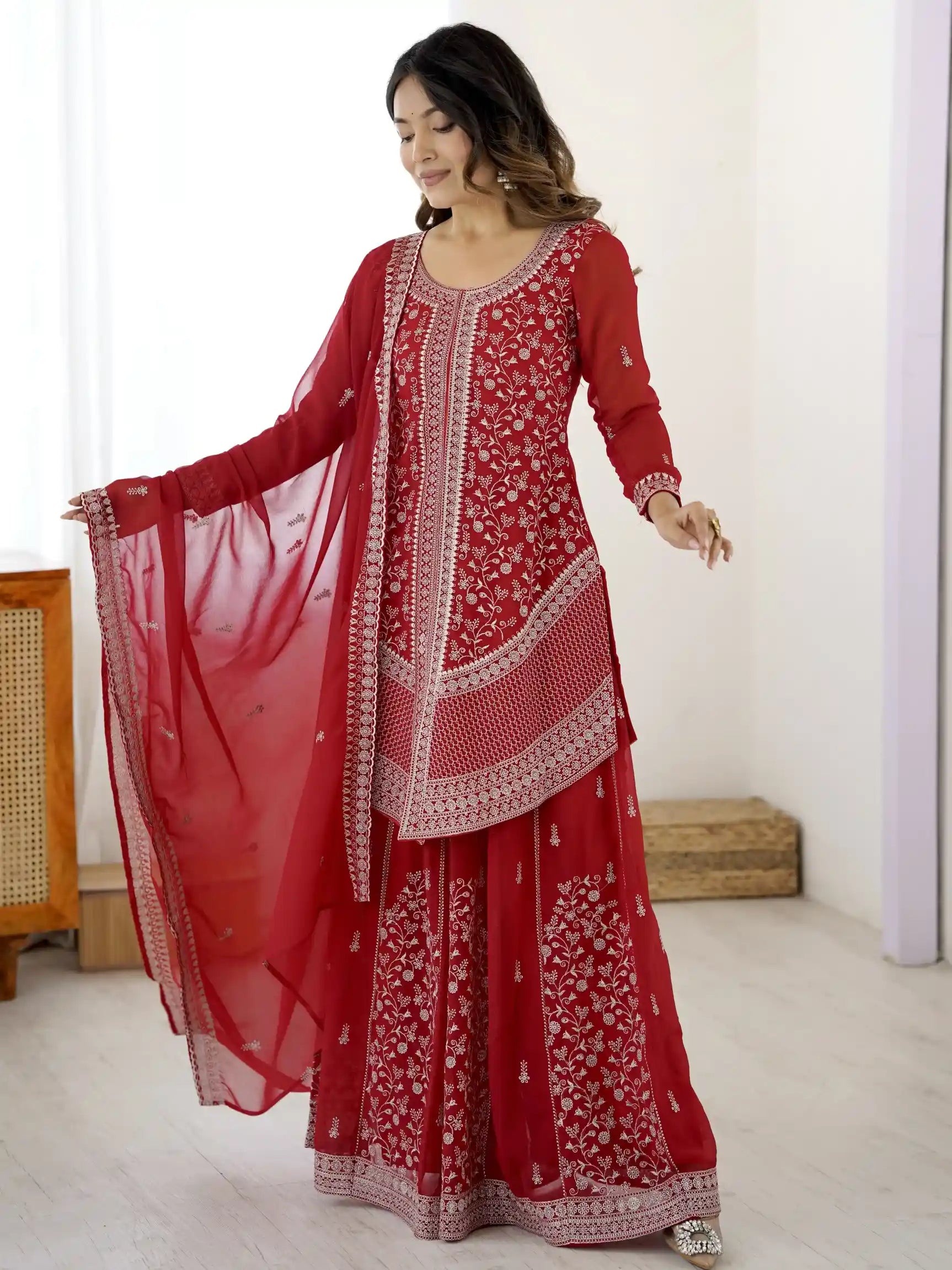 Woman wearing a red embroidered traditional outfit with a white background