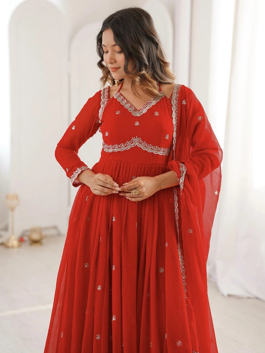Woman wearing a red dress with white embroidery in a minimalistic setting