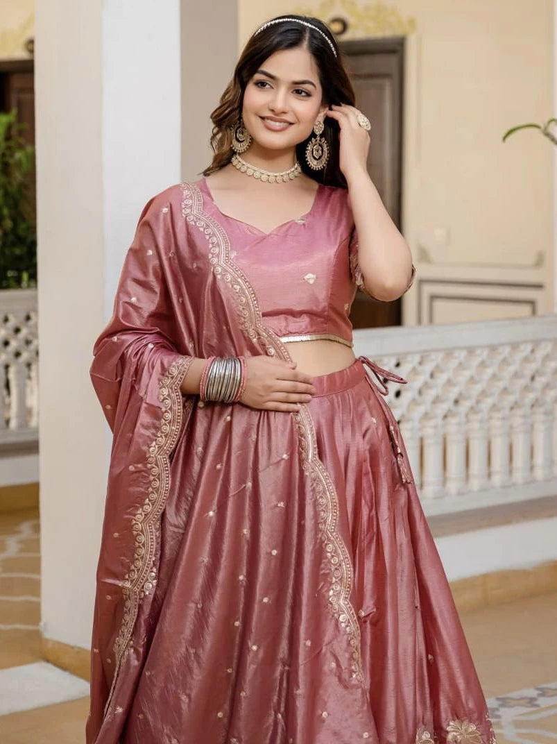 Woman in a traditional pink outfit with gold embroidery indoors.