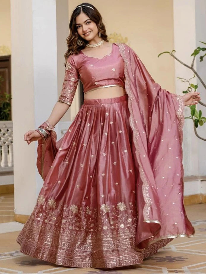 Woman in a pink traditional outfit with a matching dupatta indoors.