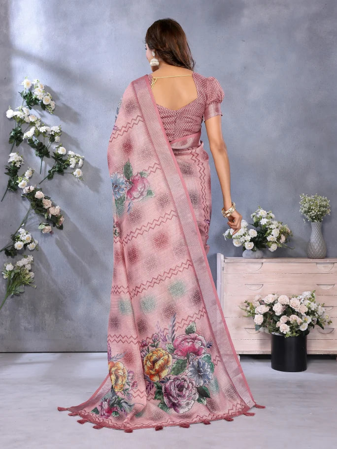 Woman wearing a pink saree with floral patterns in a room with flowers and a dresser.