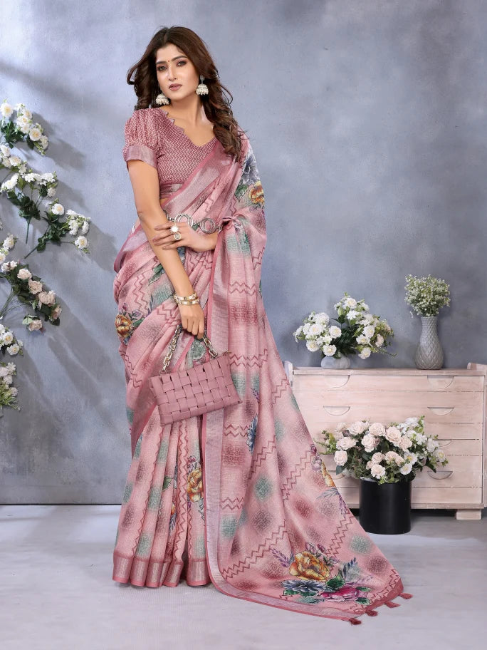 Woman wearing a pink saree with floral patterns in a decorated indoor setting.