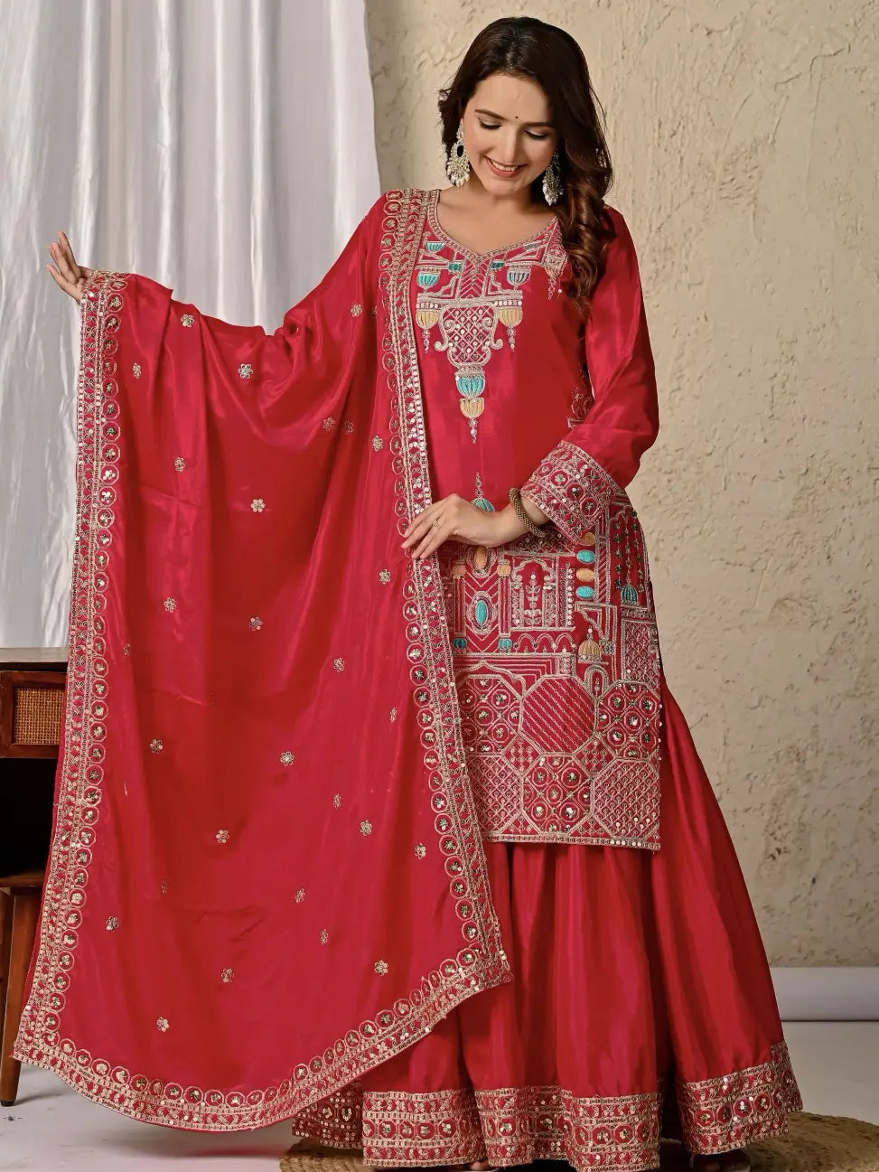 Red embroidered traditional outfit with a matching dupatta against a neutral background