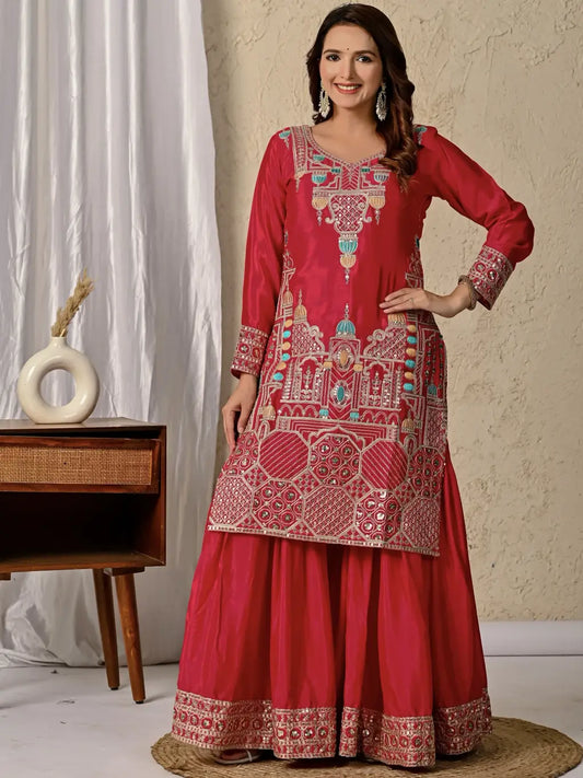Woman wearing a red embroidered traditional outfit in a room setting.