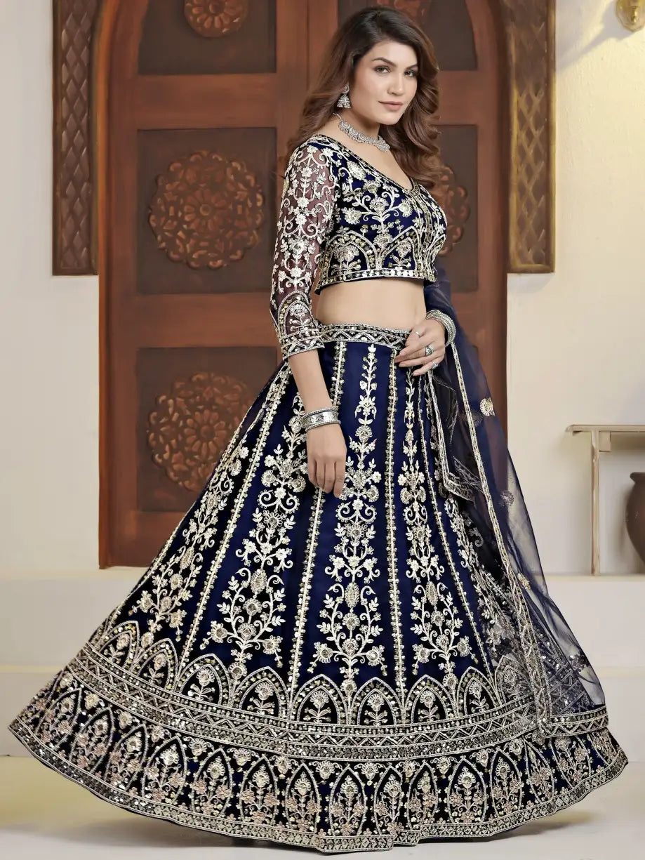 Woman wearing a traditional embroidered navy blue and white lehenga with a wooden door in the background