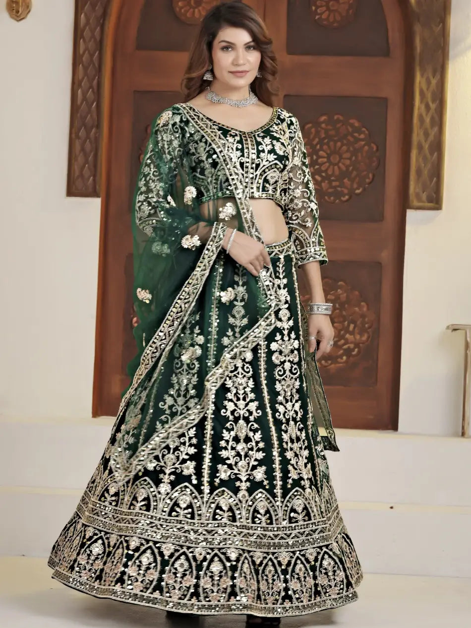 Woman wearing a green and black embroidered traditional outfit in front of a decorative wooden door.